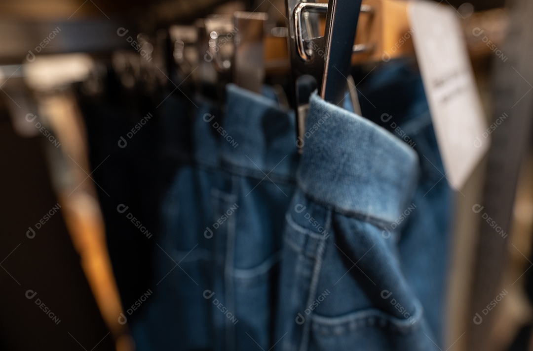 Foto desfocada de calças jeans em loja de roupas. Jeans em cabide pendurado em prateleira na loja de roupas.