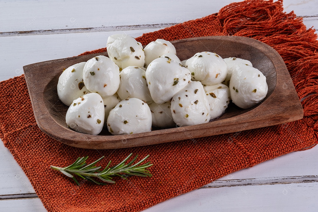 Bolas de mussarela de búfala polvilhadas com orégano em uma bandeja de madeira.