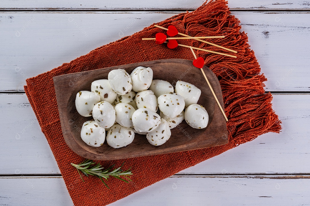 Bolas de mussarela de búfala polvilhadas com orégano em uma bandeja de madeira.