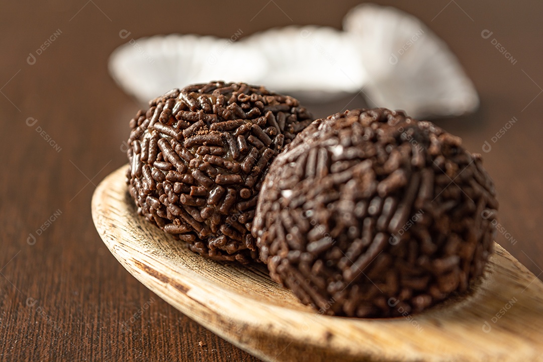 Brigadeiro brasileiro com chocolate granulado em uma colher de pau sobre a mesa de madeira.
