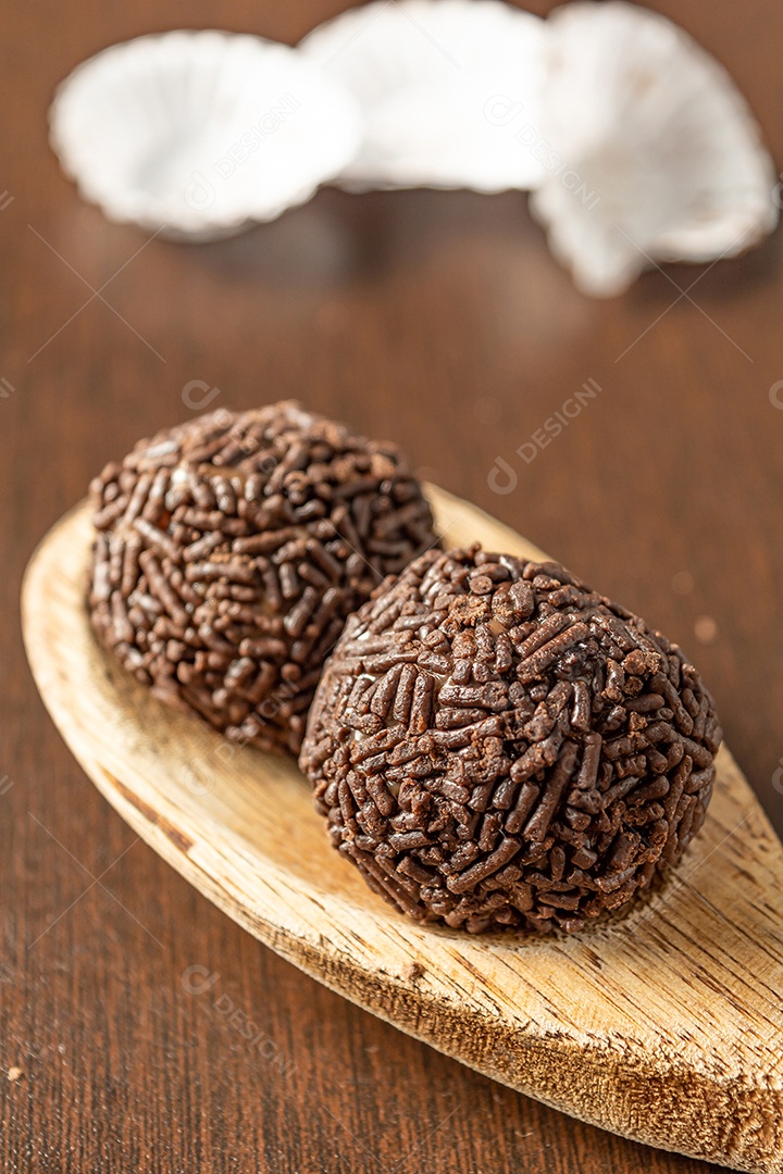 Brigadeiro brasileiro com chocolate granulado em uma colher de pau sobre a mesa de madeira.