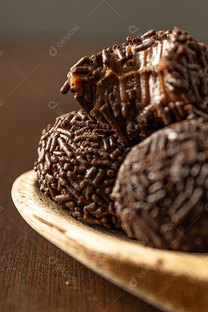 Brigadeiro brasileiro com chocolate granulado em uma colher de pau sobre a mesa de madeira.