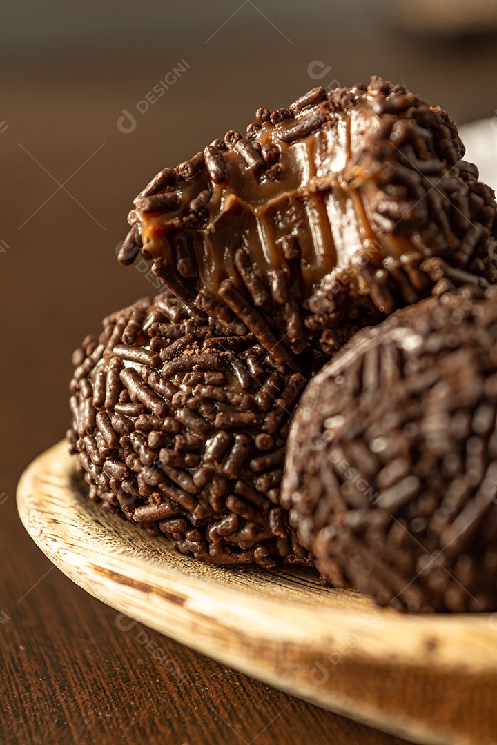 Brigadeiro brasileiro com chocolate granulado em uma colher de pau sobre a mesa de madeira.