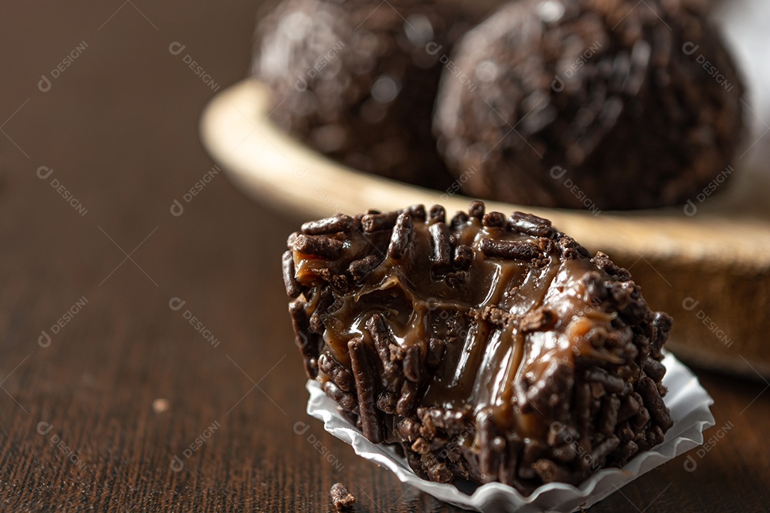 Brigadeiro brasileiro com chocolate granulado em uma colher de pau sobre a mesa de madeira.