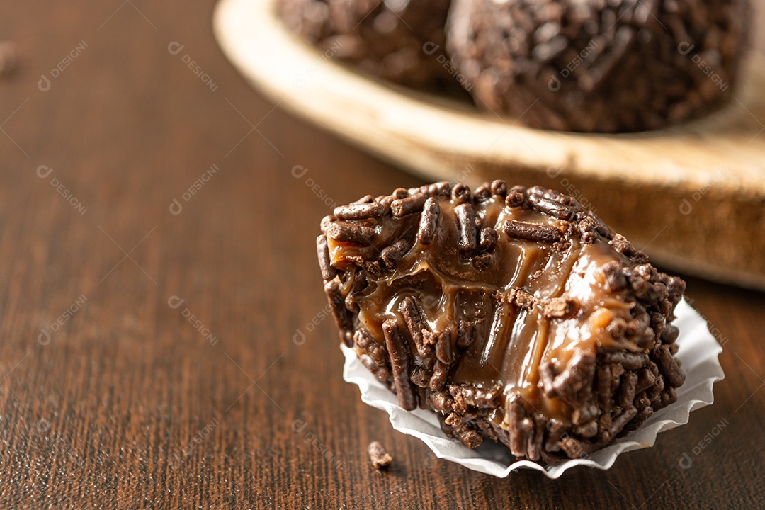 Brigadeiro brasileiro com chocolate granulado em uma colher de pau sobre a mesa de madeira.