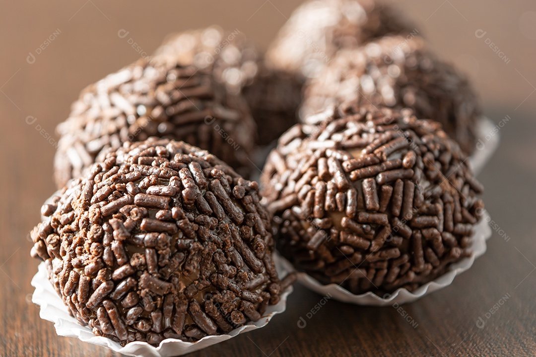 Brigadeiro brasileiro com chocolate granulado em uma colher de pau sobre a mesa de madeira.