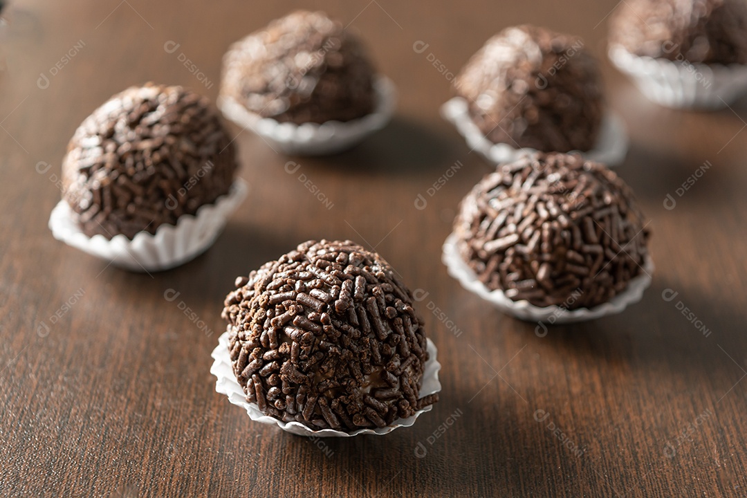 Brigadeiro brasileiro com chocolate granulado em uma colher de pau sobre a mesa de madeira.