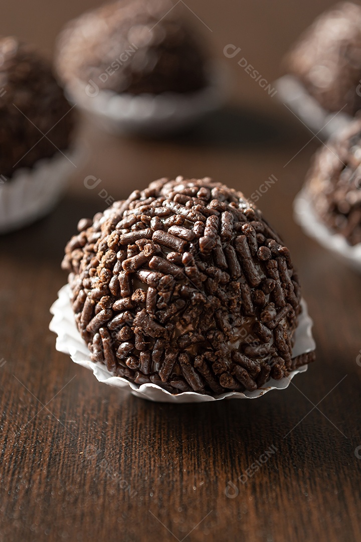 Brigadeiro brasileiro com chocolate granulado em uma colher de pau sobre a mesa de madeira.