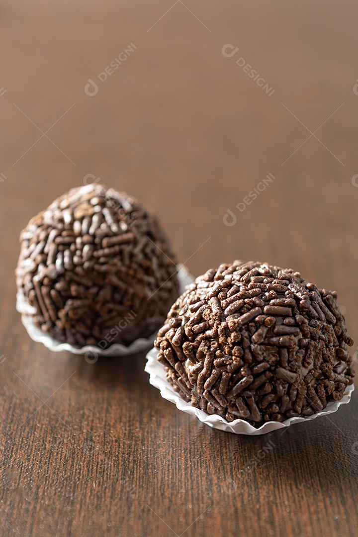 Brigadeiro brasileiro com chocolate granulado em uma colher de pau sobre a mesa de madeira.