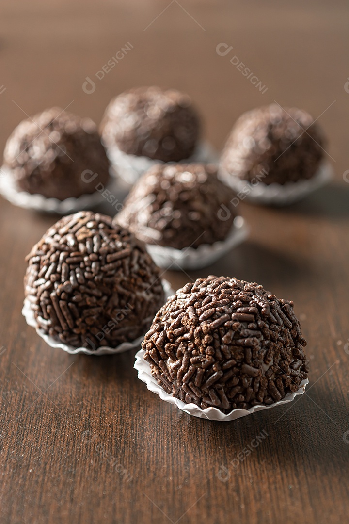 Brigadeiro brasileiro com chocolate granulado em uma colher de pau sobre a mesa de madeira.