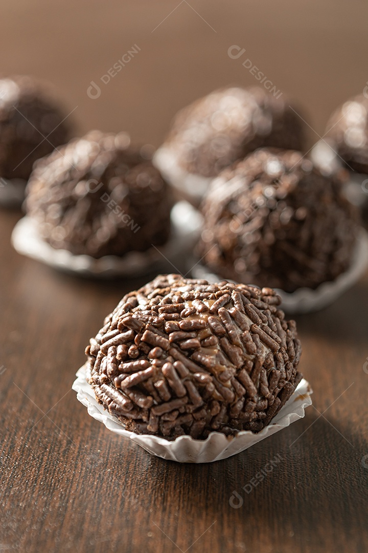 Brigadeiro brasileiro com chocolate granulado em uma colher de pau sobre a mesa de madeira.