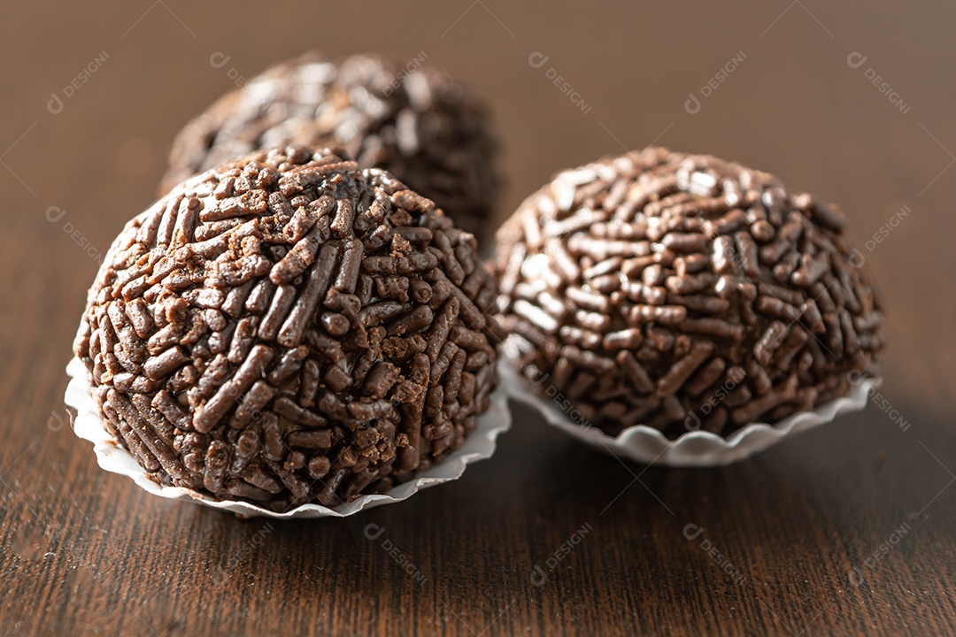 Brigadeiro brasileiro com chocolate granulado em uma colher de pau sobre a mesa de madeira.
