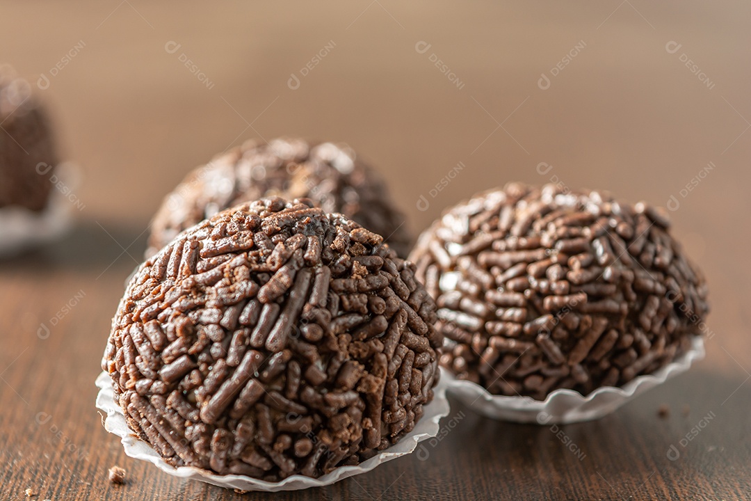 Brigadeiro brasileiro com chocolate granulado em uma colher de pau sobre a mesa de madeira.