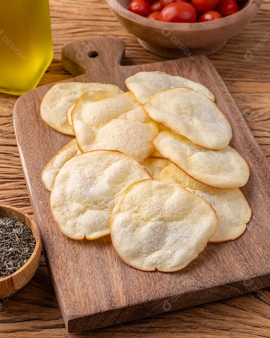 Lascas de queijo provolone defumado em uma tigela com tomate cereja e orégano sobre a mesa de madeira.