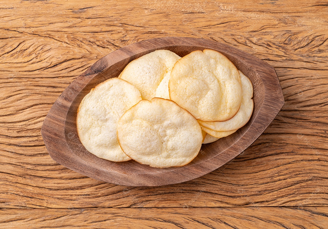 Lascas de queijo provolone defumado em uma tigela sobre a mesa de madeira.