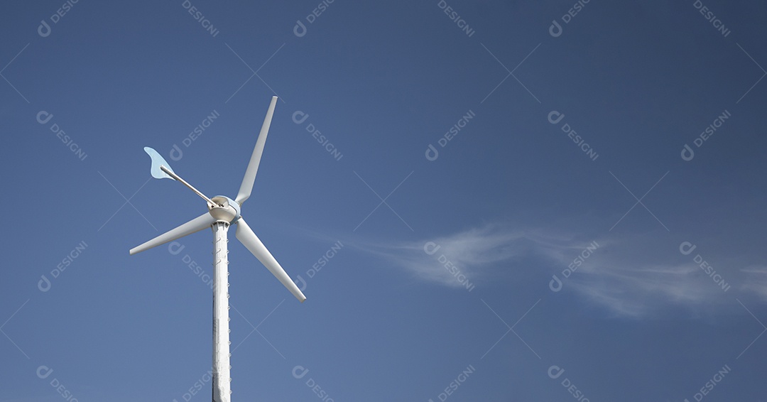 Turbina eólica com céu azul e fundo nublado.