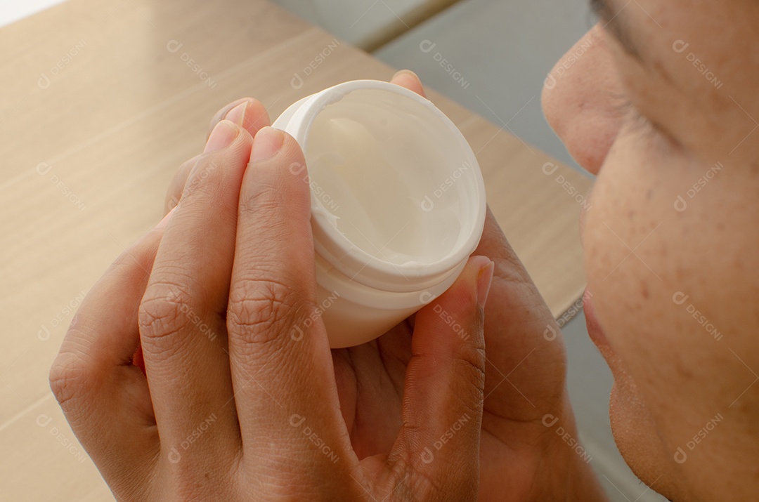 Gestos precisos, mãos femininas aplicando creme hidratante no rosto