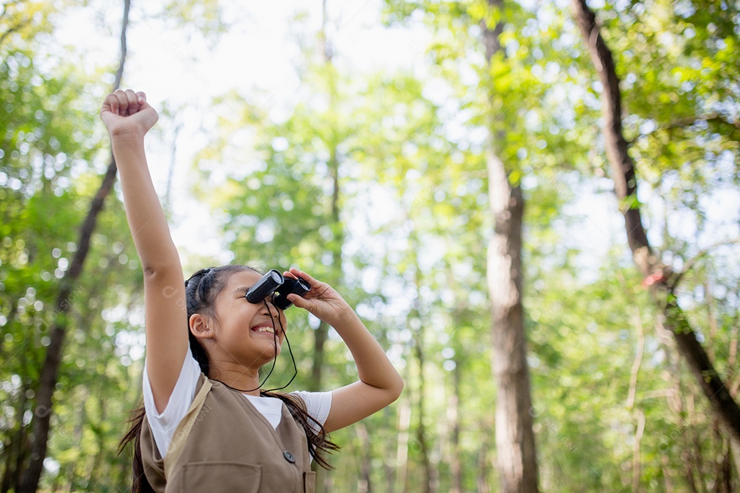 Felizes meninas asiáticas olhando para frente e sorrindo criança com os binóculos no parque.