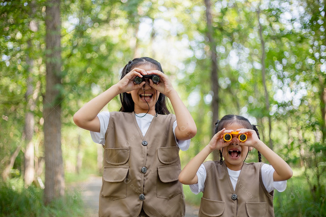 Felizes meninas asiáticas olhando para frente e sorrindo criança com os binóculos no parque.