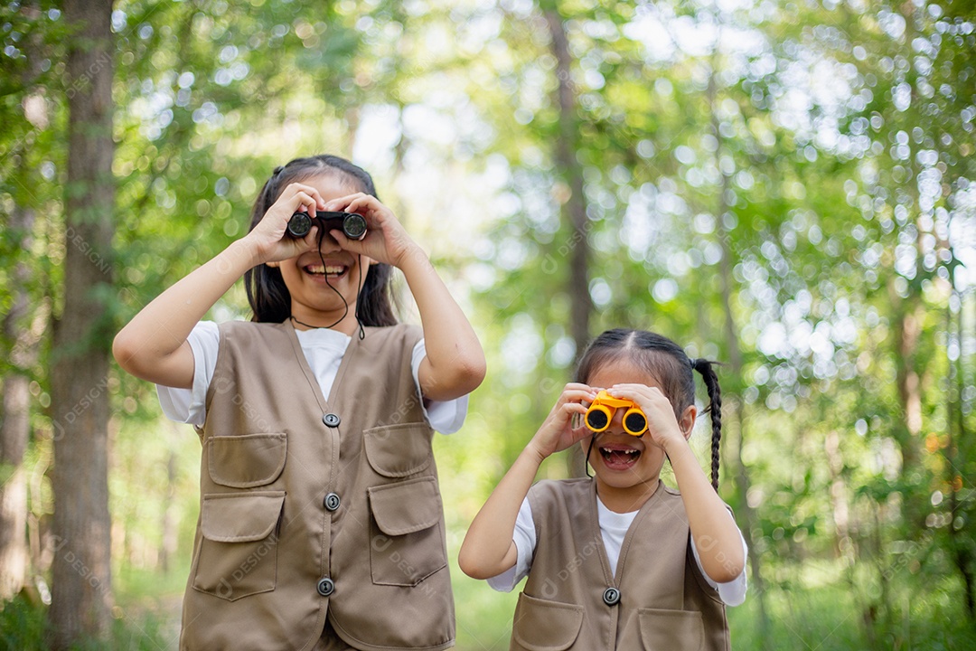 Felizes meninas asiáticas olhando para frente e sorrindo criança com os binóculos no parque.