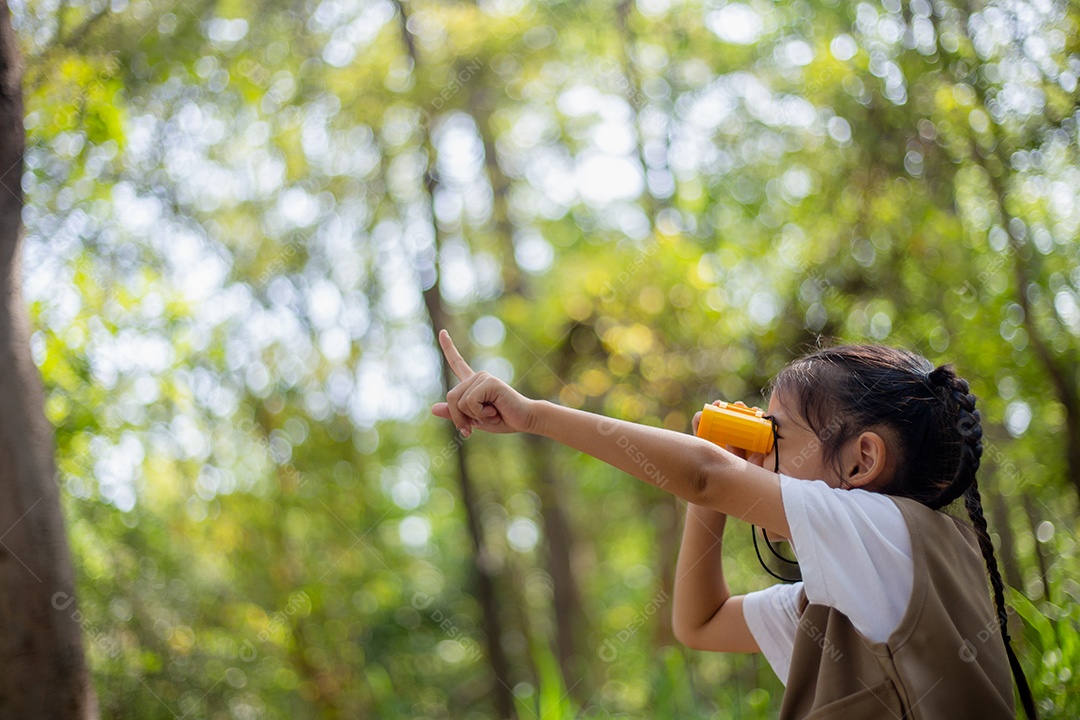 Felizes meninas asiáticas olhando para frente e sorrindo criança com os binóculos no parque.