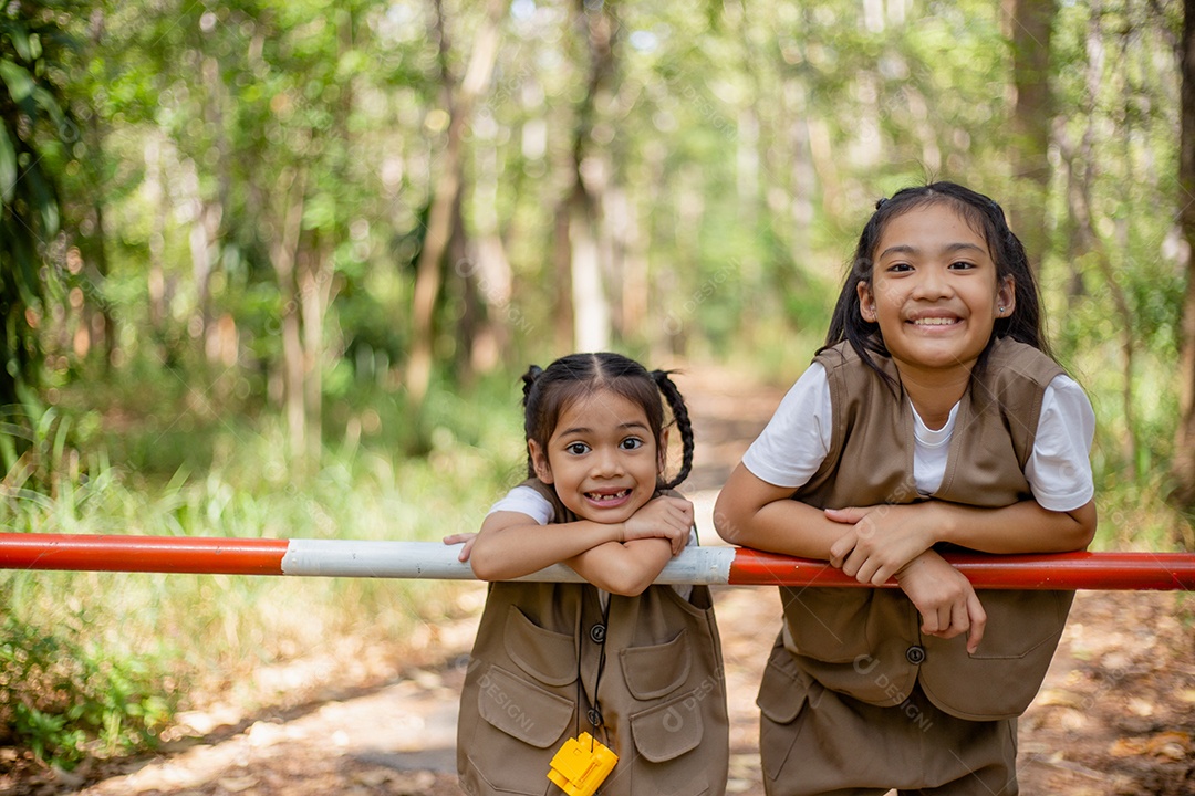 Meninas asiáticas exploram a natureza através de lupas e binóculos no parque.