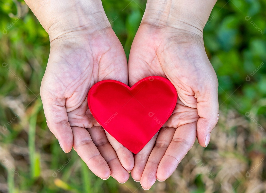 Mãos segurando um coração vermelho