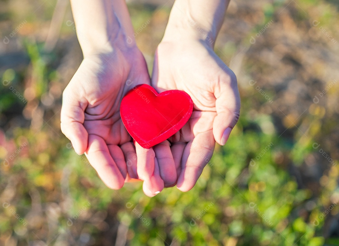 Mãos segurando um coração vermelho