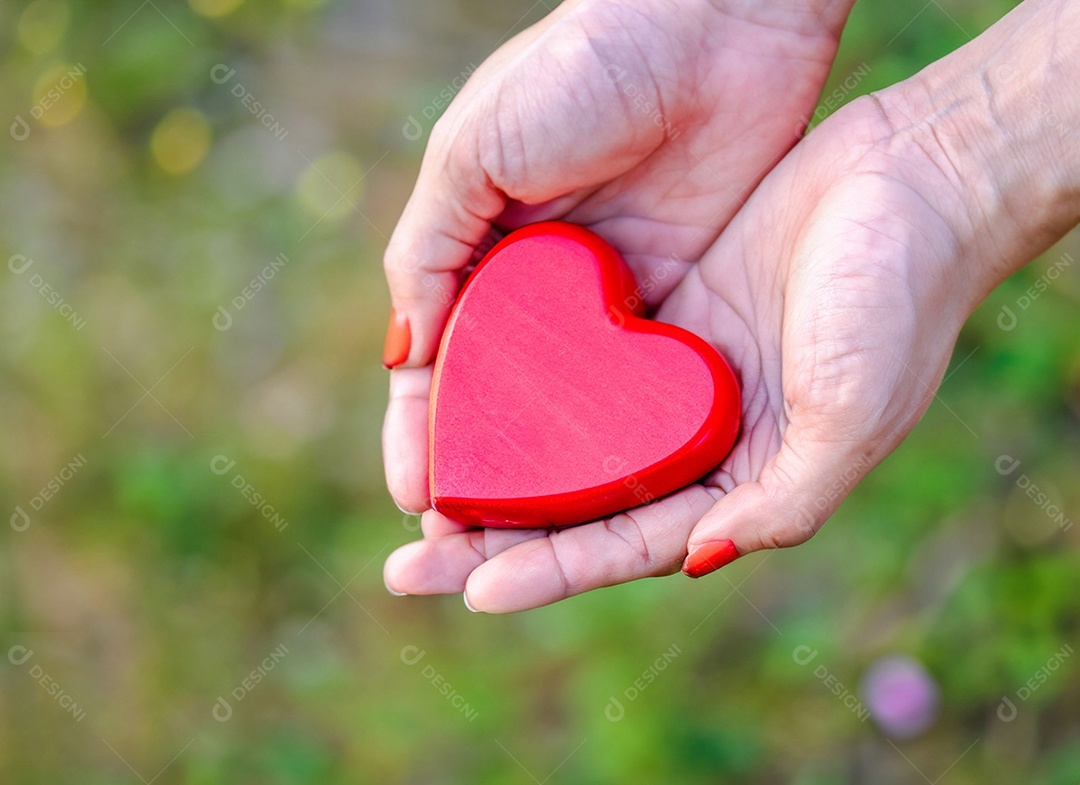 Mãos segurando um coração vermelho