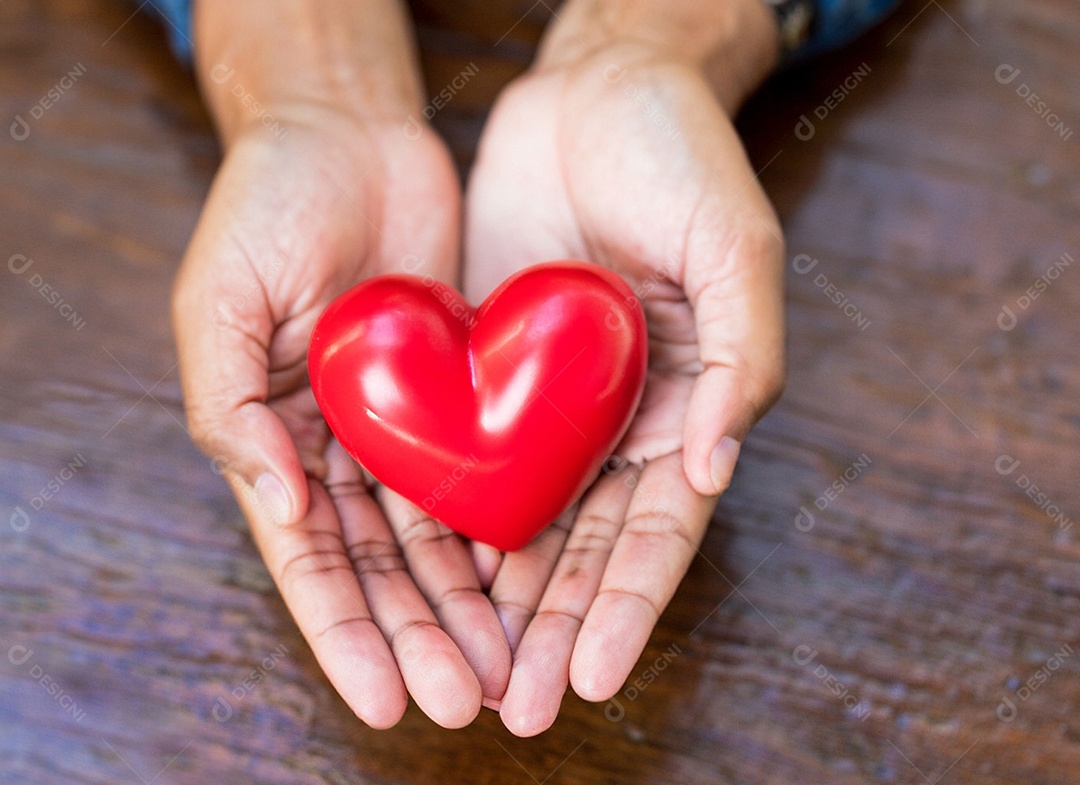 Mãos segurando um coração vermelho