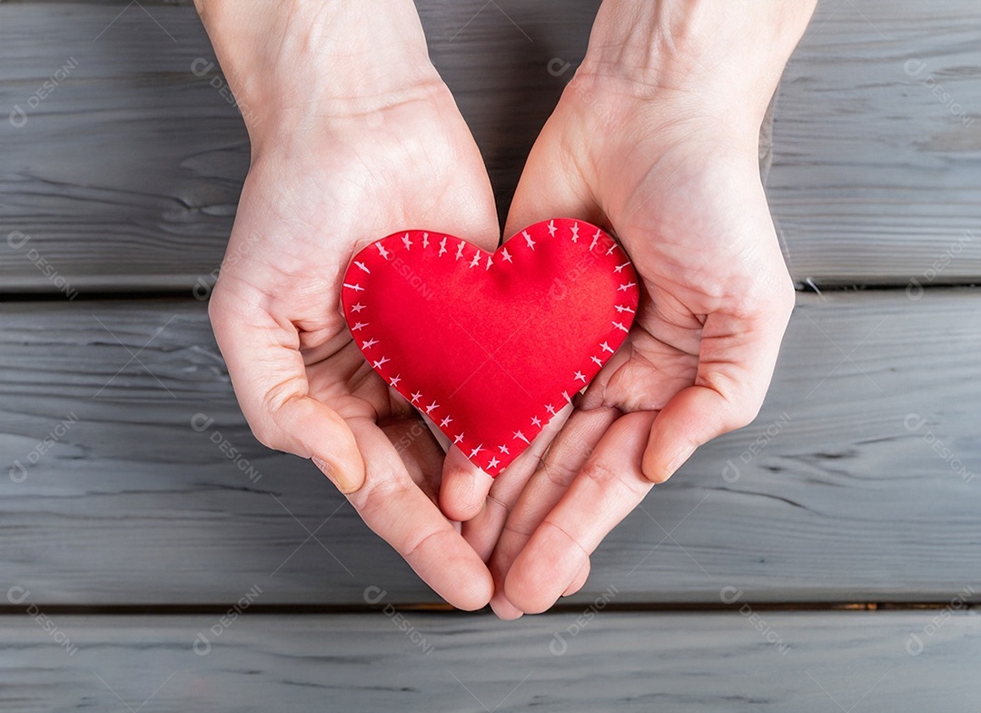 Mãos segurando um coração vermelho