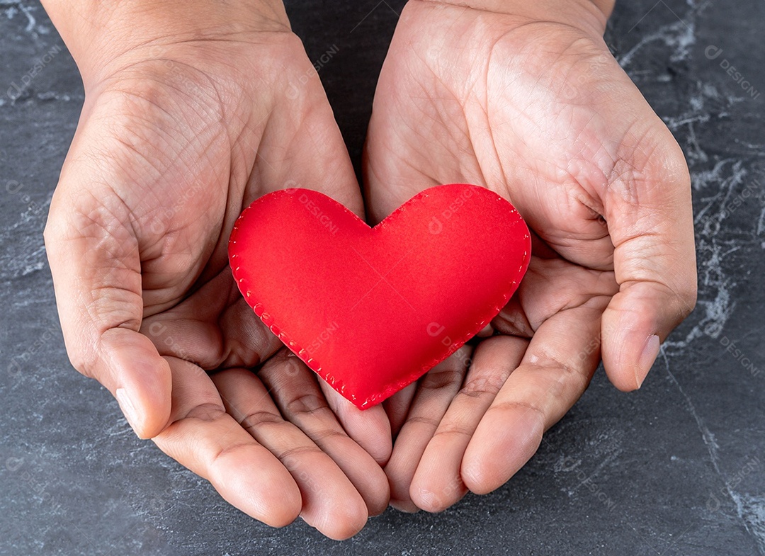 Mãos segurando um coração vermelho