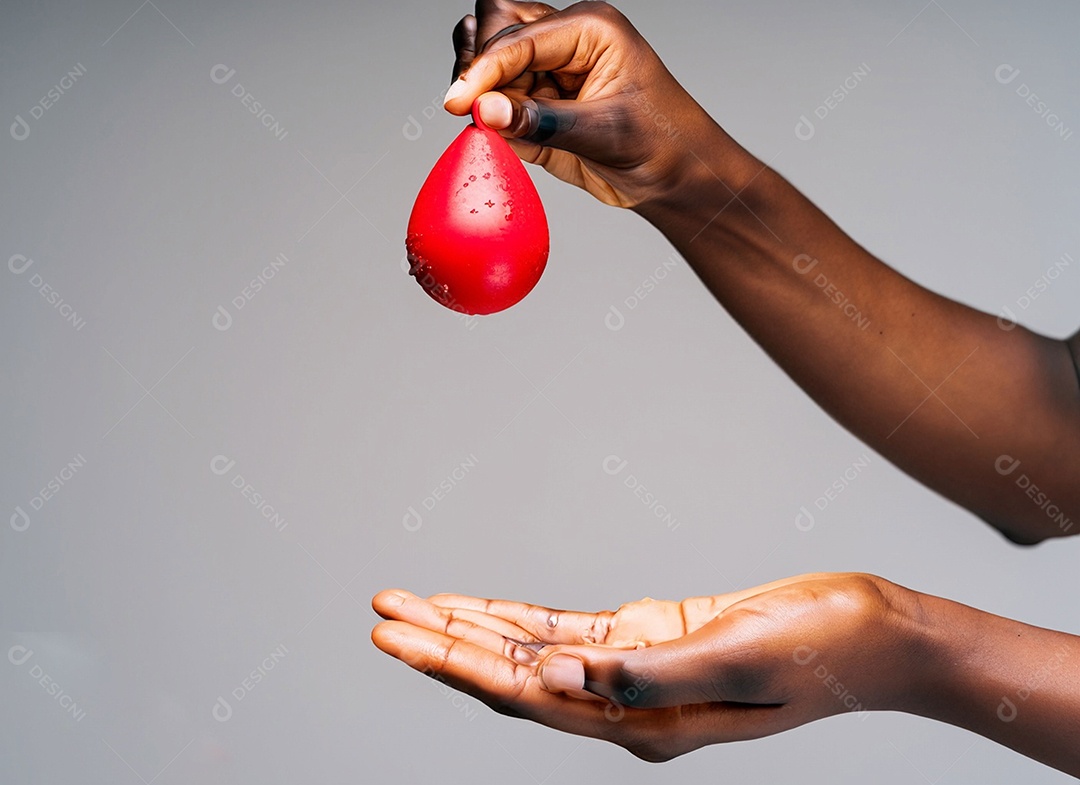 Mãos segurando uma gota vermelha