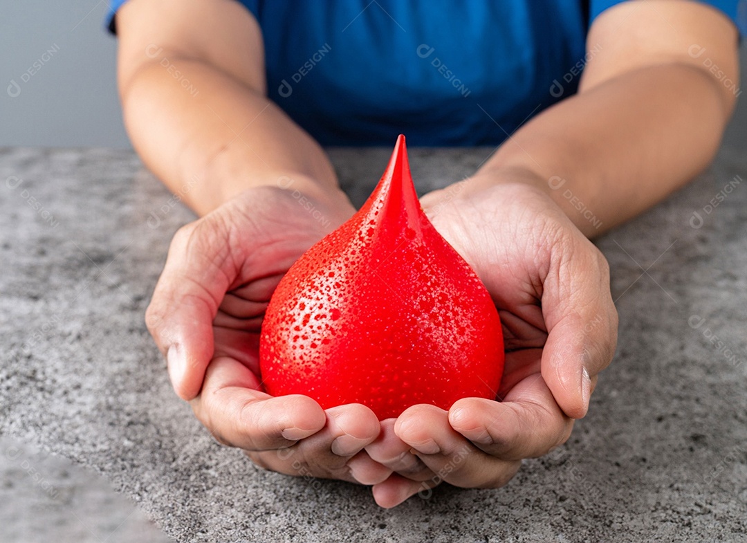 Mãos segurando uma gota vermelha