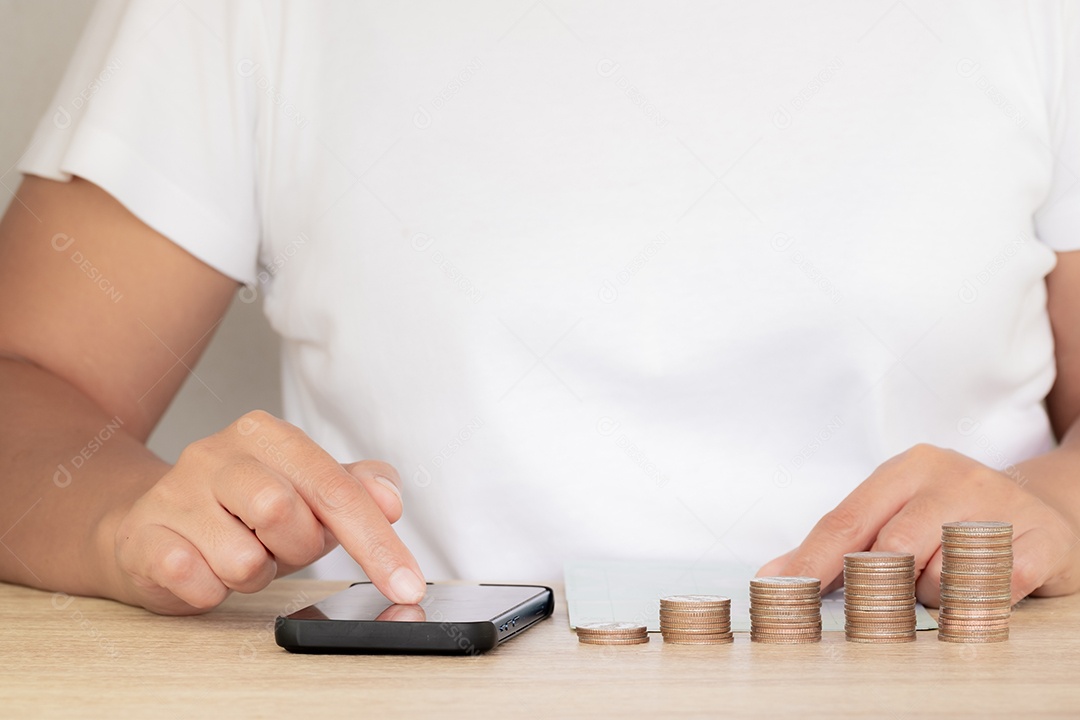 Economizando o conceito de dinheiro predefinido pela mão feminina colocando a pilha de moedas de dinheiro em crescimento