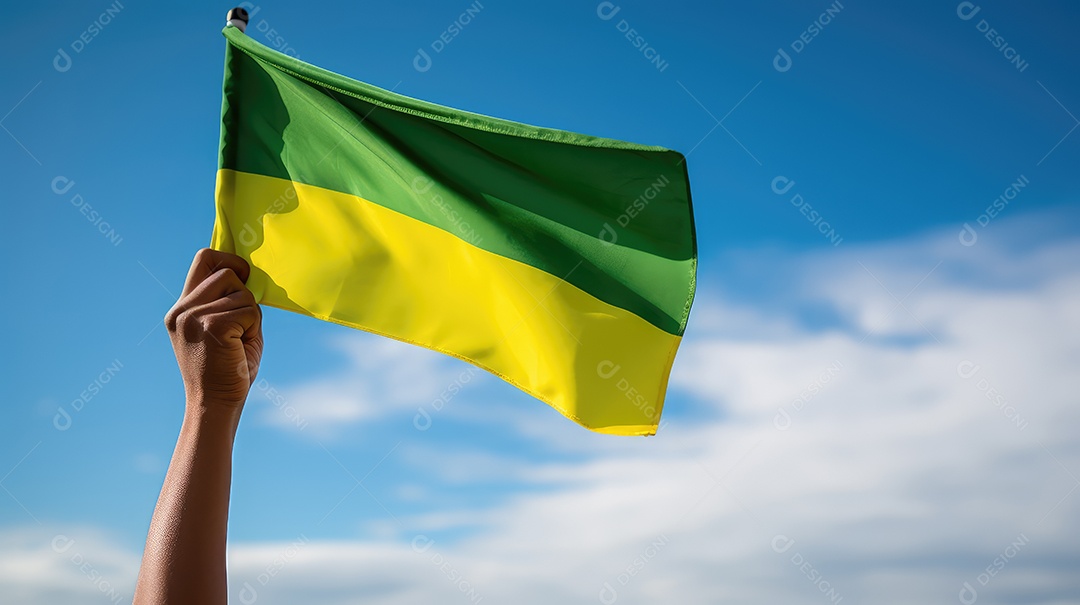Mão segurando bandeira verde e amarela contra o céu no dia da independência do Brasil e espaçamento para texto