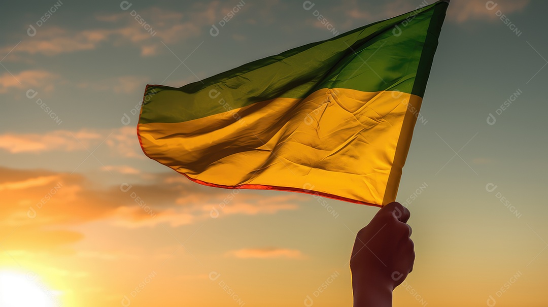 Mão segurando bandeira verde e amarela contra o céu no dia da independência do Brasil e espaçamento para texto