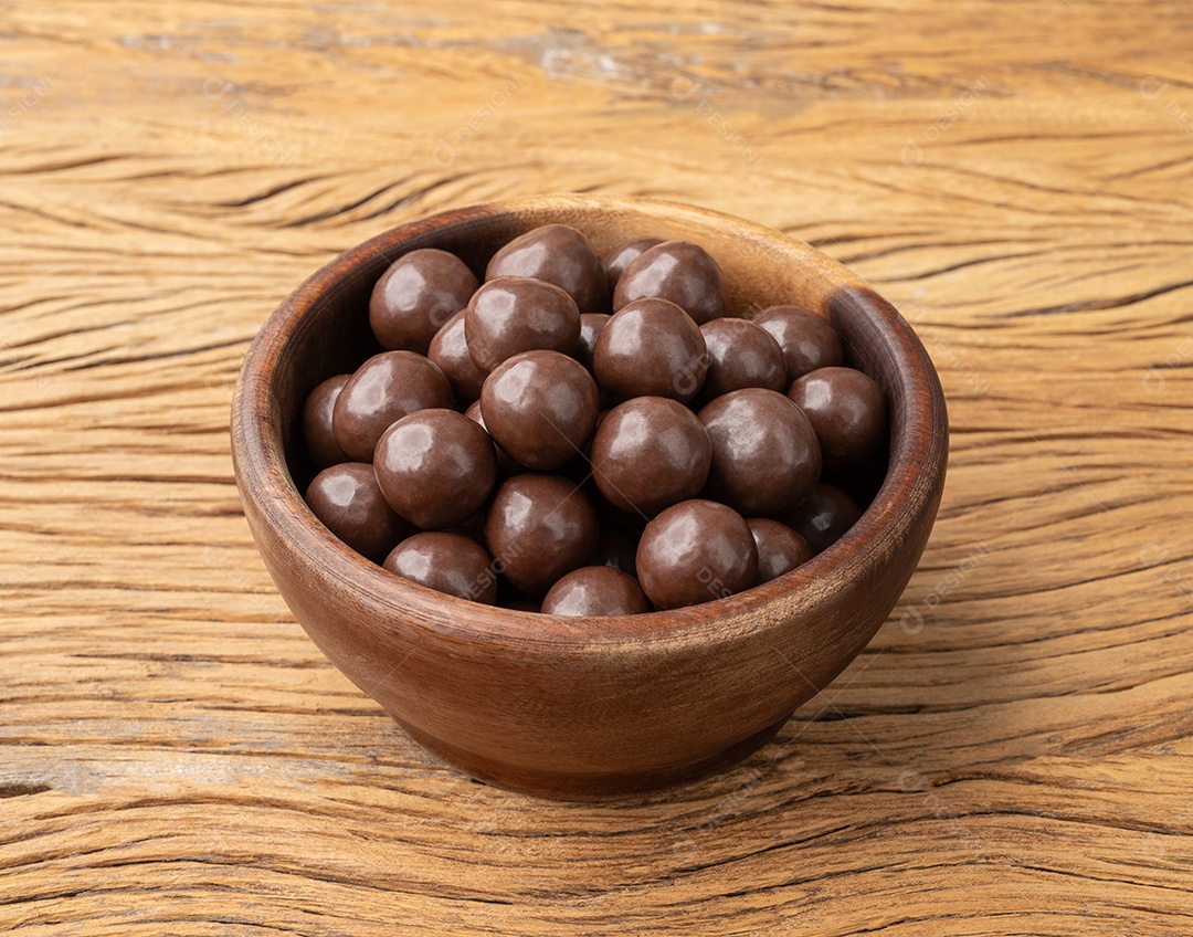 Bolas maltadas de chocolate em uma tigela sobre a mesa de madeira.