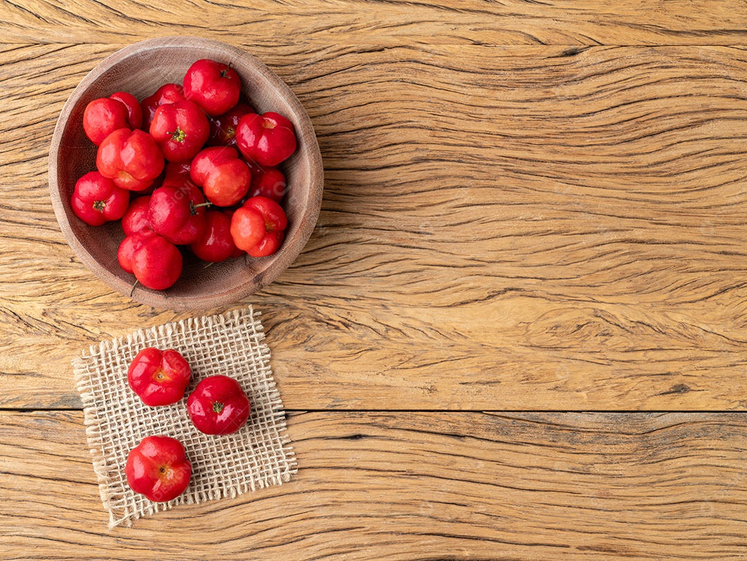 Acerolas ou cerejas de Barbados em uma tigela sobre uma mesa de madeira com espaço de cópia.