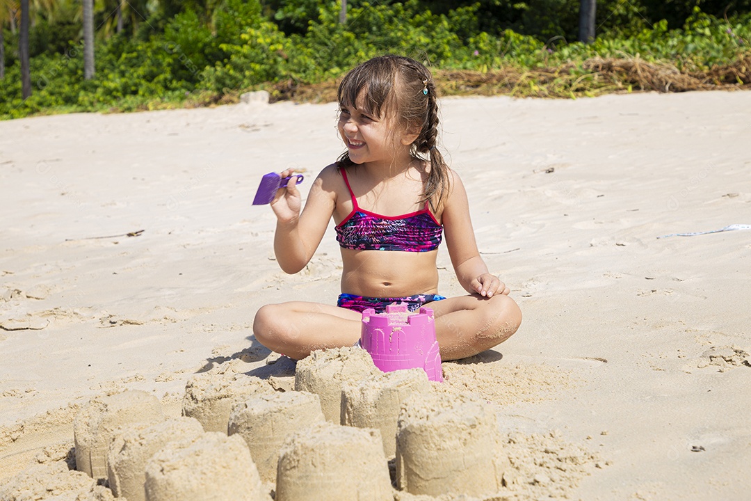 Linda menina brincando na areia da praia