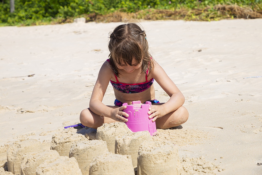 Linda menina brincando na areia da praia