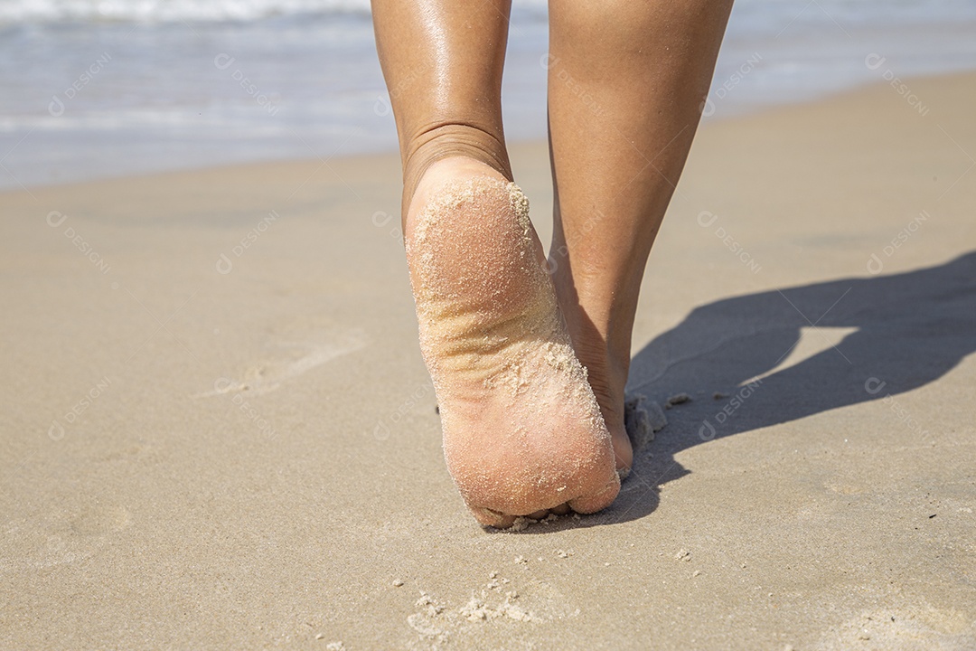 Mulher andando sobre areia da praia