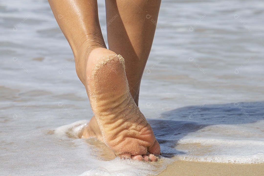 Mulher andando sobre areia da praia