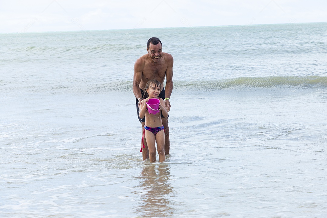 Homem e menina felizes na praia