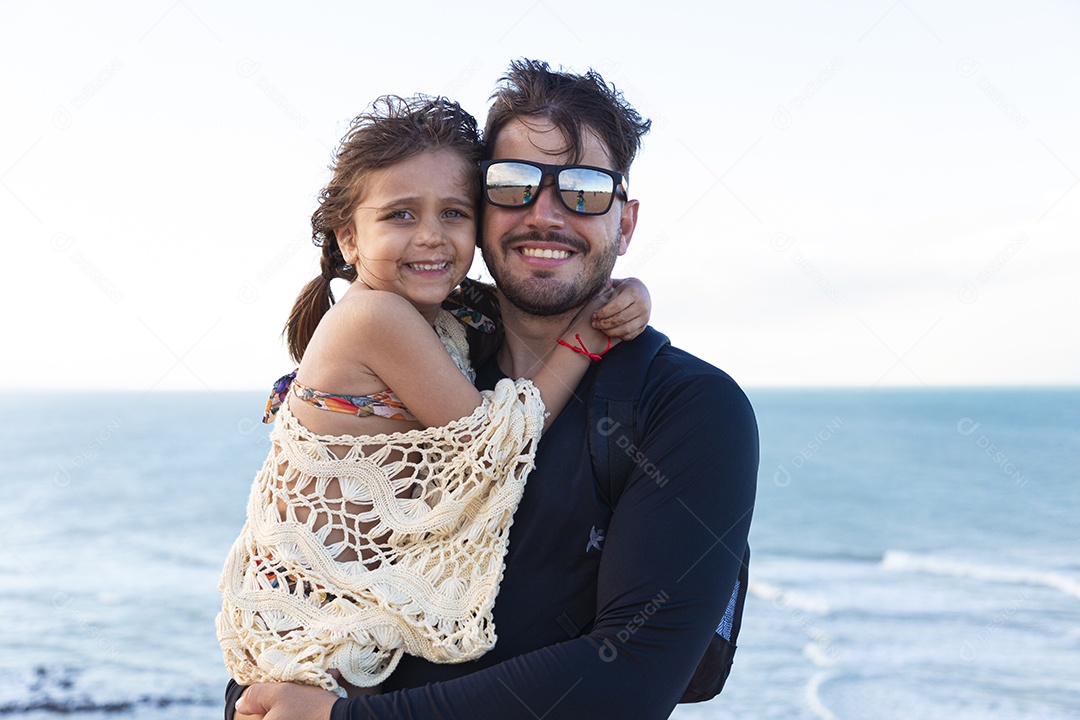 Pai e filha sorridentes na praia