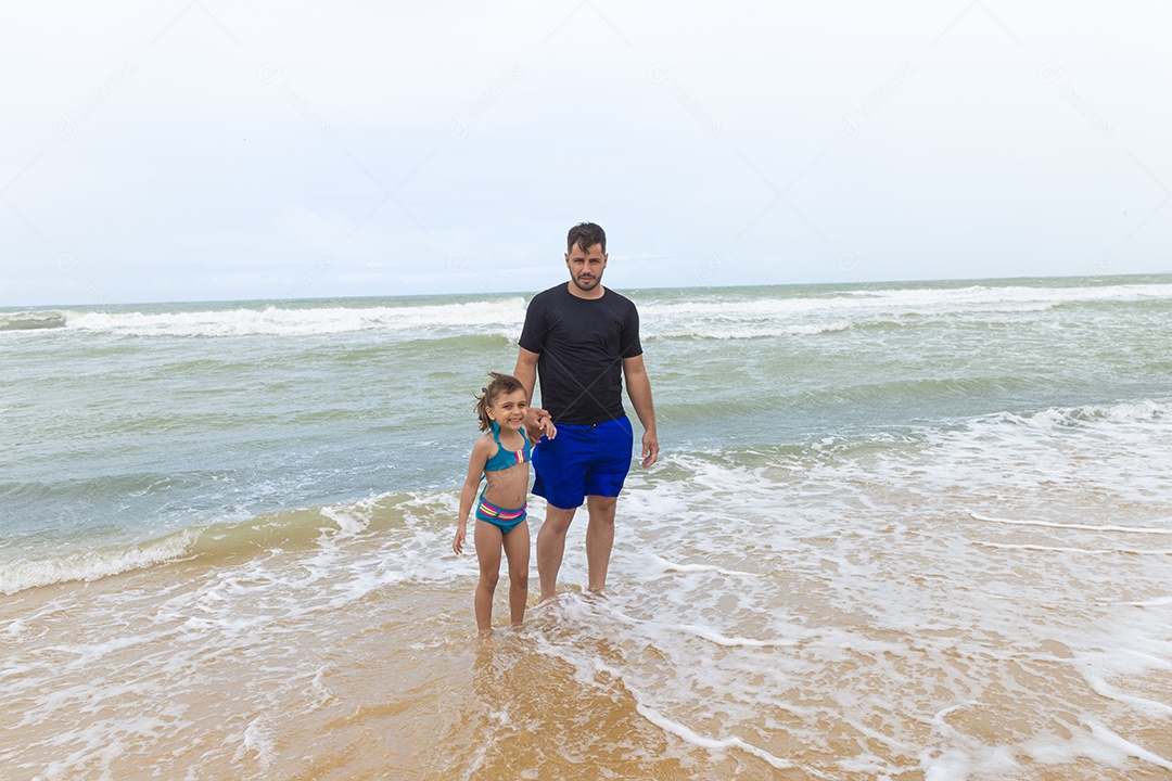 Pai e filha sorridentes na praia