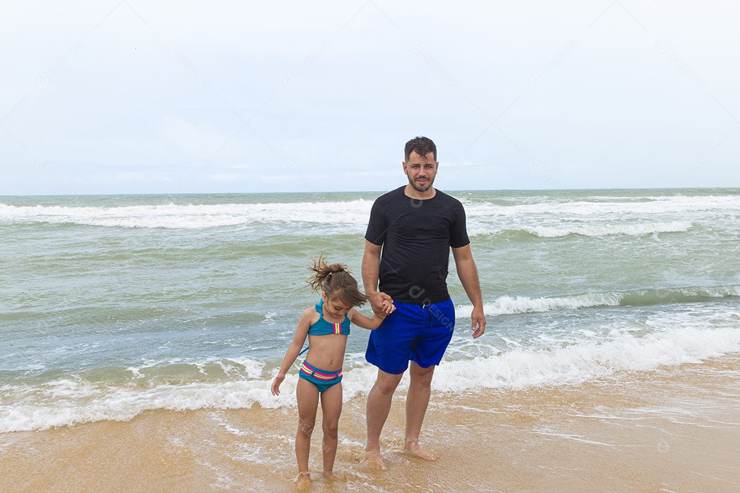 Pai e filha sorridentes na praia