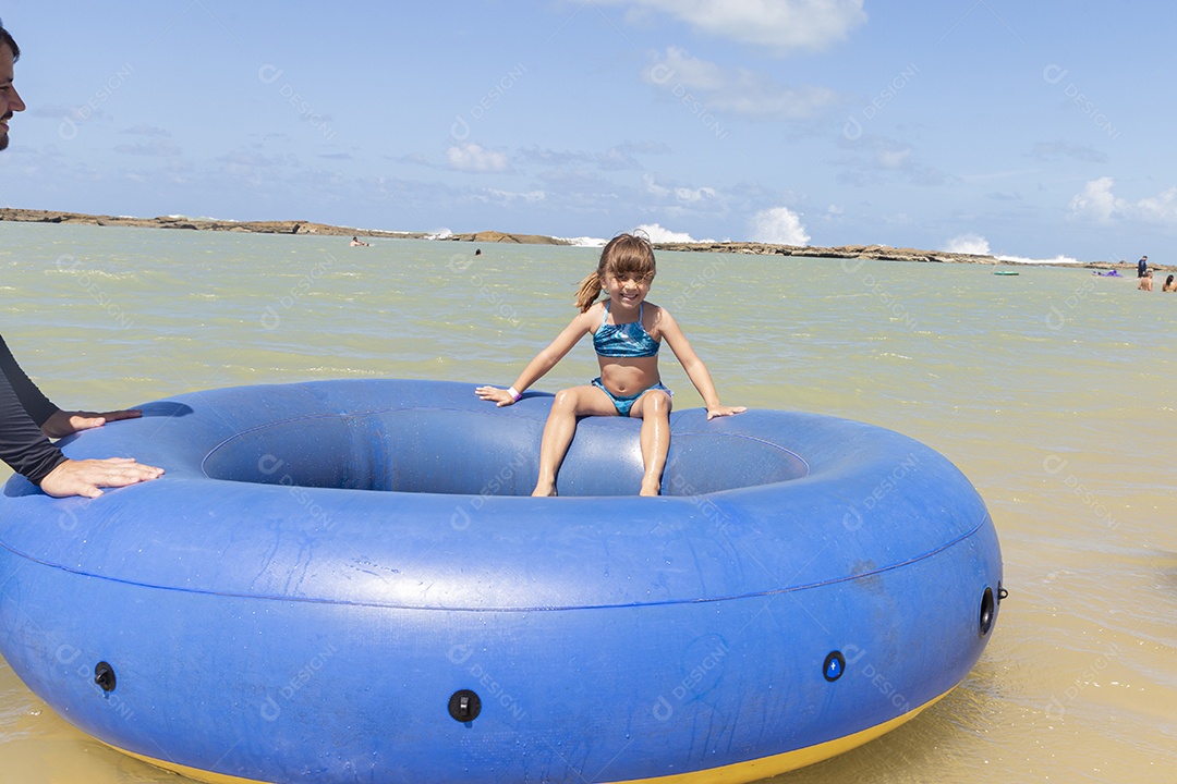 Linda garotinha sorridente na boia azul da praia
