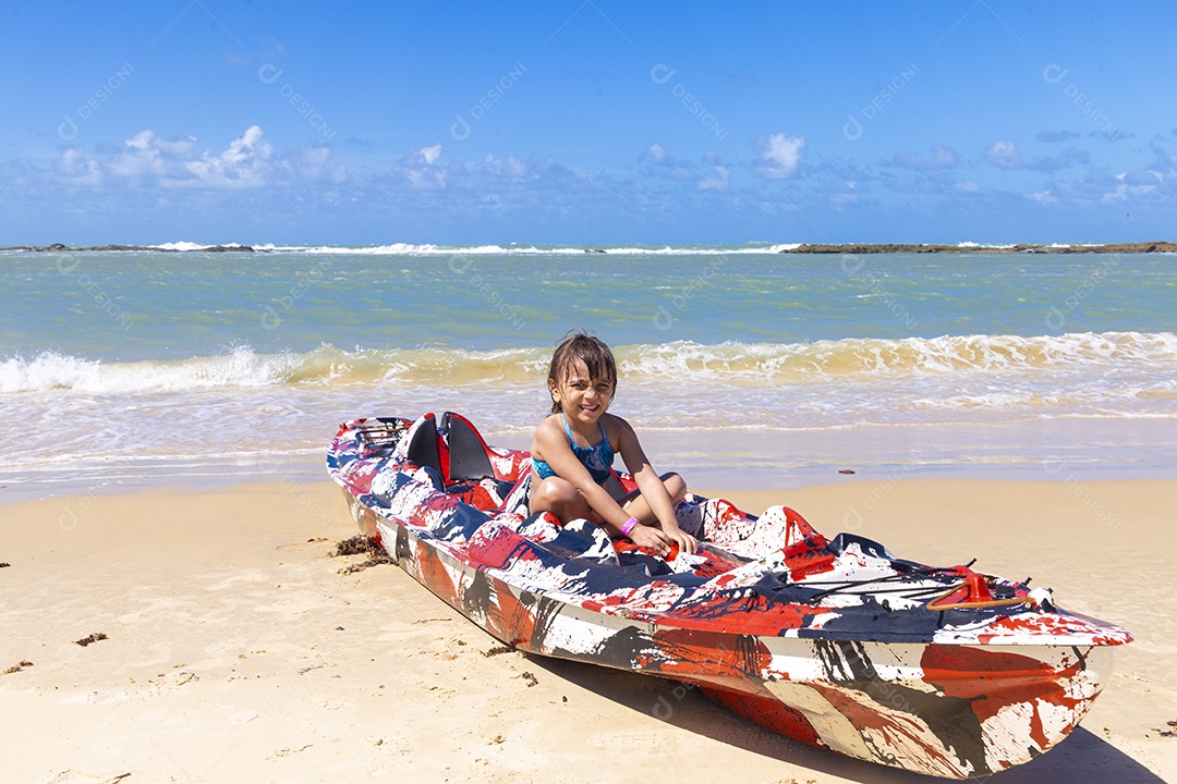 Menina sentada em caiaque na praia