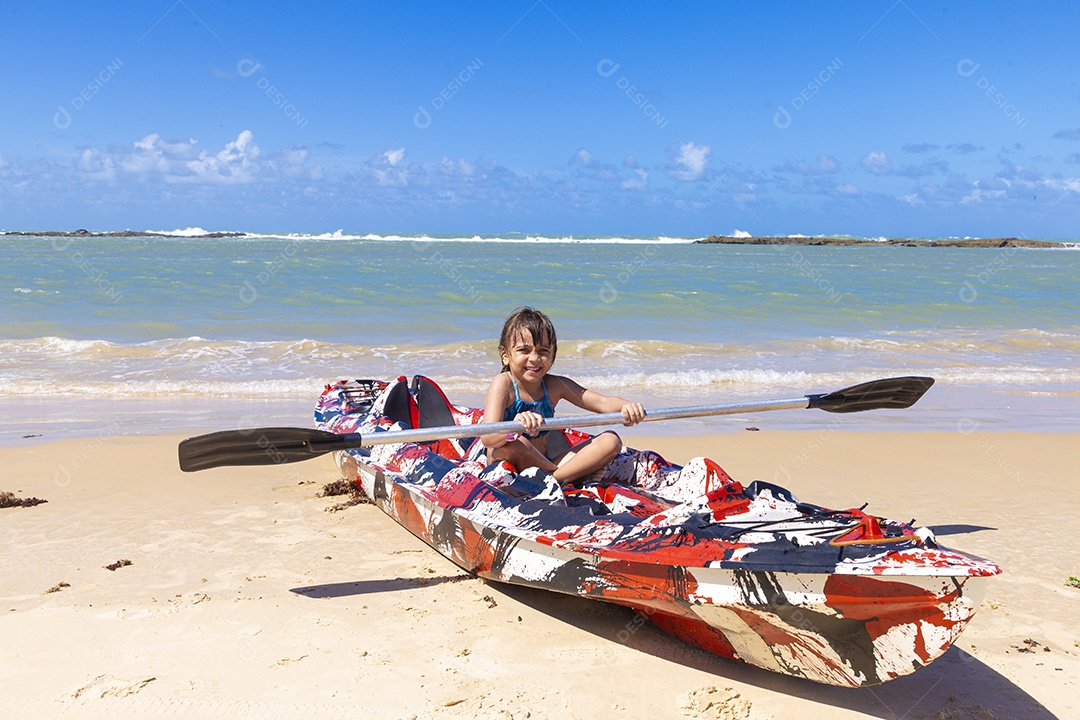 Menina sentada em caiaque na praia